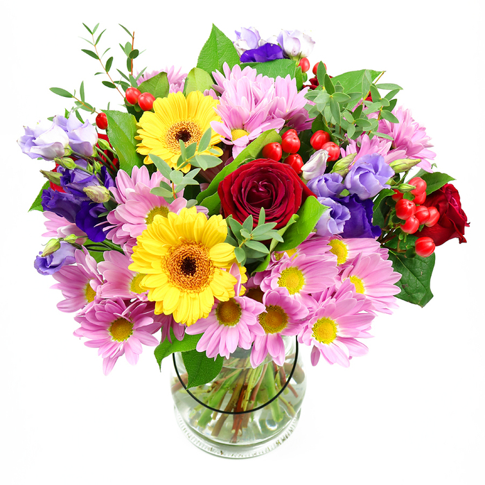 A lush, colour-rich bouquet rises confidently from a clear glass vase, its form clearly outlined against a clean white backdrop that accentuates every flower. The central feature is a cluster of deep red roses, their velvety petals spiralling inward and overlapping with a sense of depth and luxury, reminiscent of a cosy evening in a classic Earl's Court townhouse. Positioned nearby, two striking yellow gerbera daisies with dark brown-orange centres act as cheerful focal points, their round, open faces giving the arrangement a radiant, almost sunlit quality. Around these central elements, soft pink daisies or chrysanthemums spread outward in a generous ring, each flower filled with slim petals surrounding a neat yellow centre, which together add fullness and a soothing, pastel softness. Interlaced among the pinks and reds, purple and lavender lisianthus blossoms rise on slender stems, their fluted, bell-like shapes introducing a cooler, more serene note, as if echoing the calm of local garden squares tucked behind Earl's Court Road. Tucked between the petals, glossy red hypericum berries form tight, rounded clusters, injecting flashes of vivid colour and a unique texture that feels both playful and contemporary. Varied greenery weaves throughout the bouquet, with broad, dark leaves providing a solid backdrop and finer, lighter sprigs adding lift and freshness, giving the impression of a hand-gathered arrangement that might have come straight from a nearby flower stall by the station. The transparent glass vase reveals the cleanly cut stems standing in clear water, testament to careful preparation by an experienced Earl's Court florist. Together, these elements create a bouquet that feels joyful, welcoming, and versatile, ideal for marking birthdays, saying thank you, or brightening a reception desk or dining table in Earl's Court.