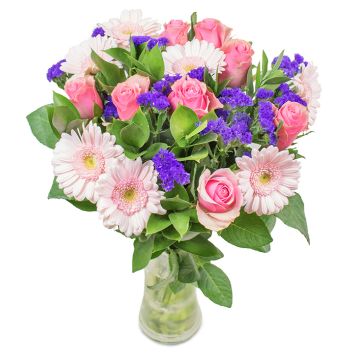 Set against a bright, white backdrop, this elegant arrangement from Earls Court Florist features seven to nine soft and medium pink roses, many with petals gently unfurling in their signature spiral pattern-a design reminiscent of refined window boxes found along Nevern Place. Complementing the roses are about five to seven pale pink gerbera daisies, their large circular heads and nearly white centres giving the bouquet a buoyant, modern feel. Clusters of vivid purple statice peek through, offering bold colour contrast and a delightfully unexpected visual twist. Rich, deep green leaves surround the blossoms, enhancing the arrangement's sense of freshness and adding to its generous silhouette, much like the vibrant plantings in Courtfield Gardens. Displayed in a clear glass vase, the visible stems and pristine water further highlight the bouquet's freshness and hand-crafted quality. Ideal for celebrations such as birthdays, anniversaries, or as a lasting accent for a stylish Earl's Court residence, this bouquet conveys warmth, celebration, and an elevated sense of local contemporary style.